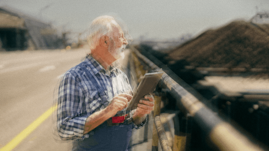 Older engineer using a tablet while inspecting an industrial worksite.