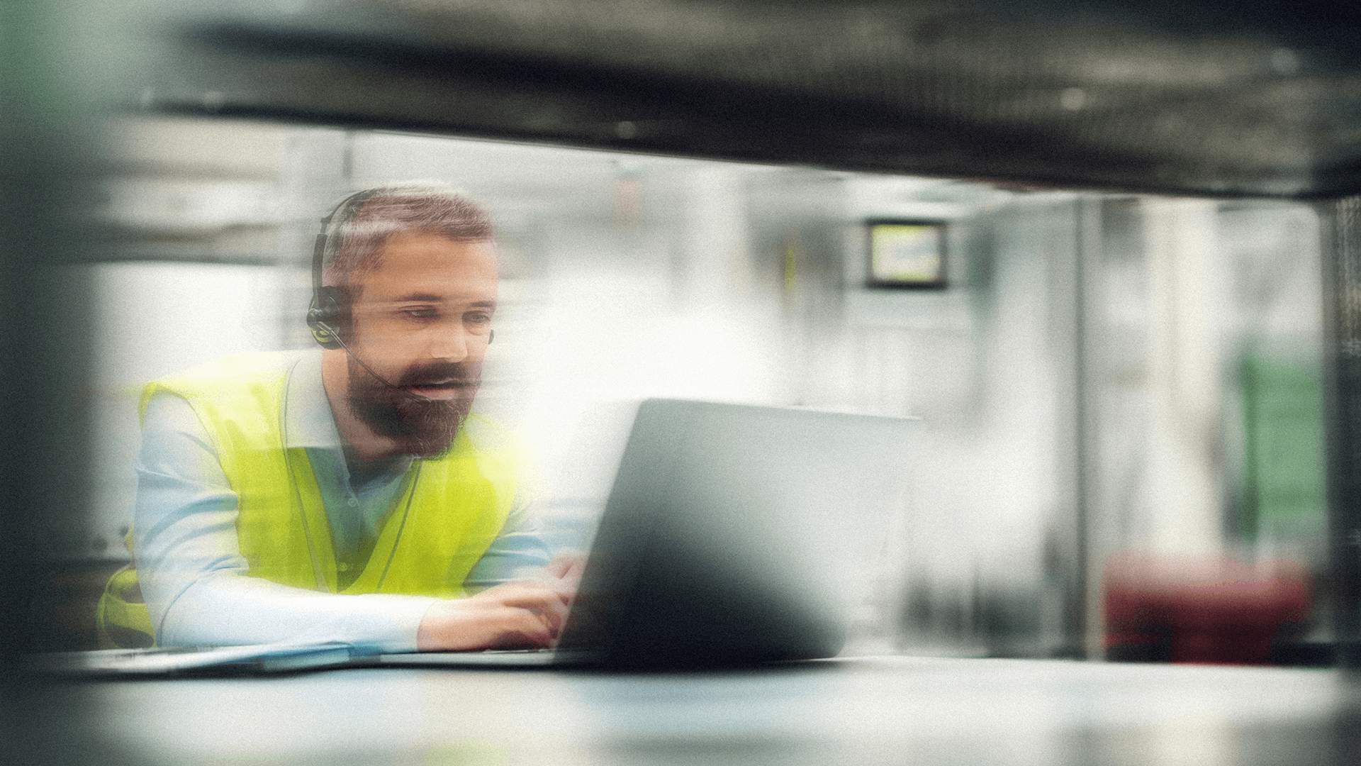 Engineer in high-vis vest using a headset and laptop for communication